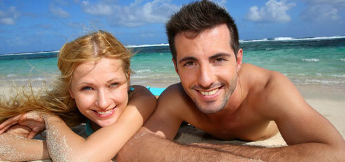 Picture of a smiling couple showing their happiness with their visit to Costa Rica for plastic surgery.  The woman is resting her head on her arm and both are facing the camera with a big smile.