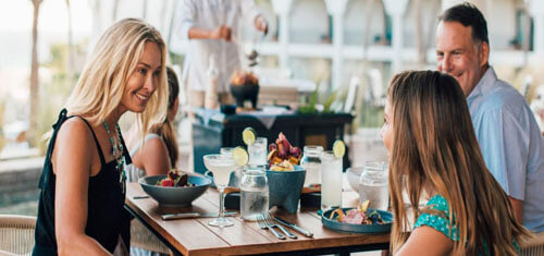 Picture of a happy guest dining in San José, Costa Rica.  The picture is of an attractive woman with long sandy blonde hair, wearing a black blouse, and sitting at a table with companions.