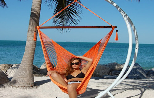 Picture of a woman in a two piece bikini lying in a hammock on the beach in Jaco