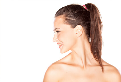 Picture of a woman with long brown hair, slightly turned to the side of the camera and happy with her perfect ear surgery procedure she had with top plastic surgeons in beautiful San José, Costa Rica.  The angle of the camera clearly shows one ear.