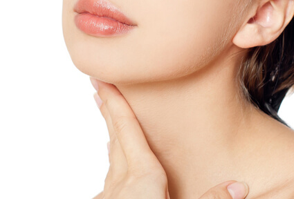 Picture of a woman with short brown hair, turned slightly away from the camera, and happy with her perfect neck lift procedure she had with top plastic surgeons in beautiful San José, Costa Rica.  The woman has her hand on her neck showing the results.