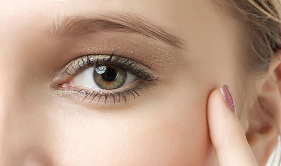 Picture of a woman, facing the camera and happy with her perfect eyelid lift procedure she with Costa Rica MedVentures in beautiful San José, Costa Rica.  The woman has her hand to the side of her face and is pointing to the side of her eye with her index finger.