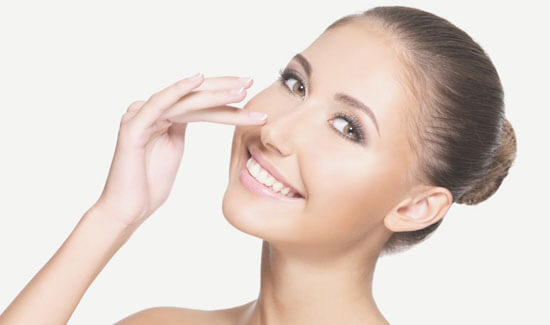 Picture of a woman, facing the camera and happy with her perfect nose surgery procedure she had with Costa Rica MedVentures in beautiful San José, Costa Rica.  The woman has her hand to the side of her nose and is pointing to where she had the surgery.